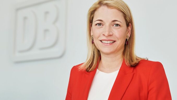Evelyn-Palla Evelyn Palla, bestuursvoorzitter van de Deutsche Bahn, in een rode blazer bij het DB-logo.