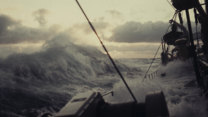 detlef_sturm Een schip vecht tegen metershoge golven tijdens een zware storm op zee, met donkere wolken en opspattend water rondom het dek.