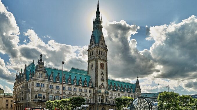 Stadhuis van Hamburg met zon achter de toren en druk stadsleven op de Rathausmarkt
