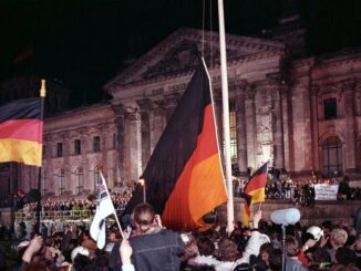 Menigte viert de Duitse eenwording op 3 oktober 1990 voor het Rijksdaggebouw in Berlijn, met Duitse vlaggen en een grote zwart-rood-gouden vlag.