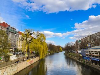 Zicht op de Maybachufer in Berlijn met de Ankerklause, water, bomen en mensen langs het Landwehrkanal.