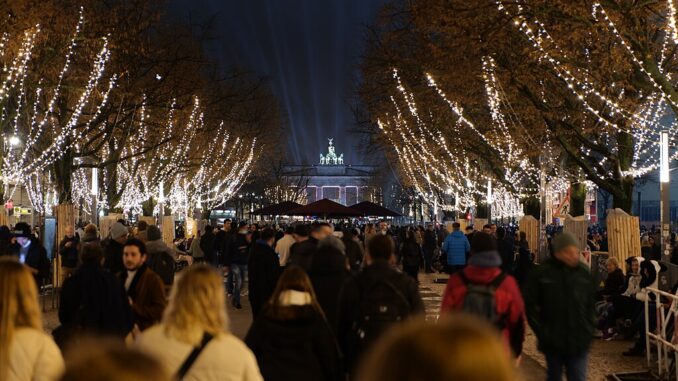 Drukke Unter den Linden in Berlijn met feestverlichting en zicht op het Brandenburger Tor tijdens Oud & Nieuw.
