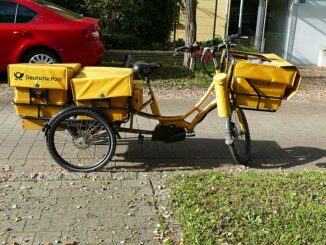 Een gele bezorgdriewieler van de Deutsche Post, geparkeerd langs de straat in München.