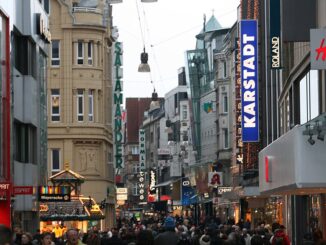 Winkelende mensen in de winkelstraat Westenhellweg in Dortmund met verlichte gevels en winkels.