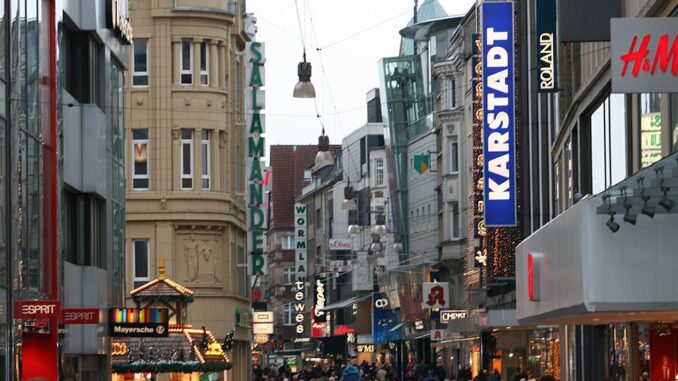 Winkelende mensen in de winkelstraat Westenhellweg in Dortmund met verlichte gevels en winkels.
