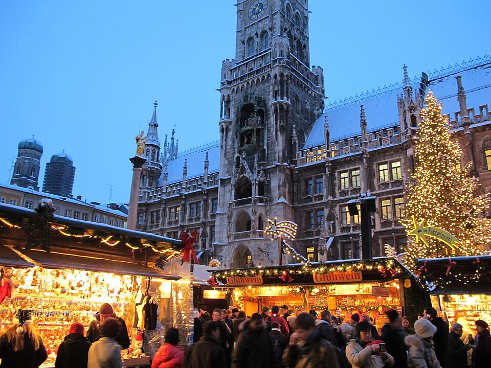 Kerstmarkt op de Marienplatz in München met verlichte kraampjes en het stadhuis op de achtergrond.