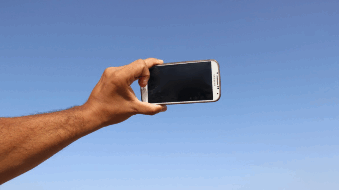 Hand houdt een smartphone omhoog, symbool voor stiekeme opnamen in de openbare ruimte