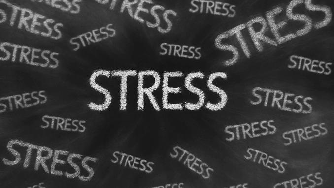 Stressbeeld met het woord STRESS in witte krijtletters op een zwart schoolbord, herhaald in chaotisch patroon.