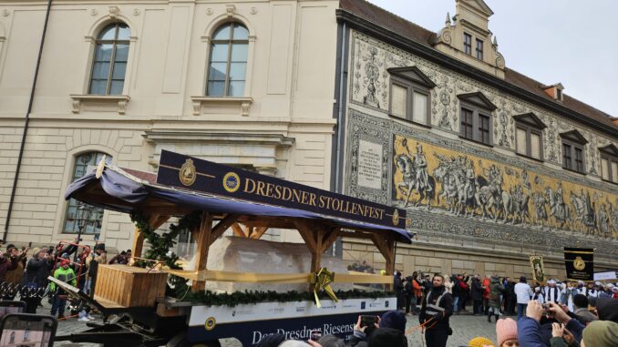 Optocht tijdens het Stollenfest in Dresden met de reuzenstol, voor het Fürstenzug-mozaïek, omringd door publiek.