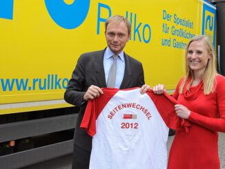 Marie-Christine Ostermann en Christian Lindner tonen een T-shirt met de tekst Seitenwechsel 2012 tijdens een bedrijfsbezoek.