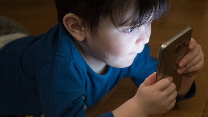 Kind kijkt op smartphone, passend bij het debat in Duitsland over leeftijdsgrenzen voor sociale media