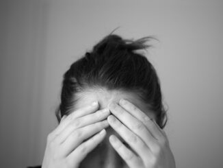 Persoon houdt het voorhoofd vast