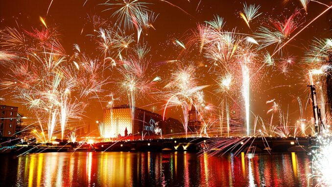 Vuurwerk boven de skyline van Berlijn tijdens oud en nieuw, weerspiegeld in de rivier