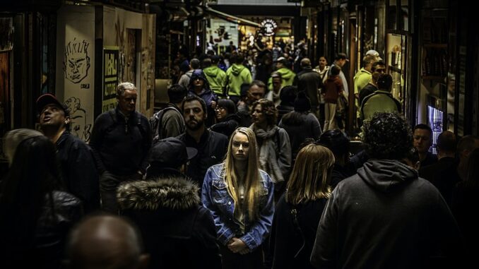 Vrouw staat eenzaam tussen een grote menigte mensen in een drukke stad