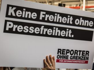 Demonstrant in Berlijn met bord “Geen vrijheid zonder persvrijheid” van Reporter zonder Grenzen
