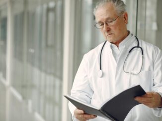 Oudere arts in ziekenhuisgang met dossier in de hand als illustratie bij artsentekort in Duitsland