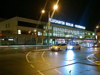 Luchthaven Berlin-Schönefeld bij avond met verlichte terminal en taxi’s voor de ingang