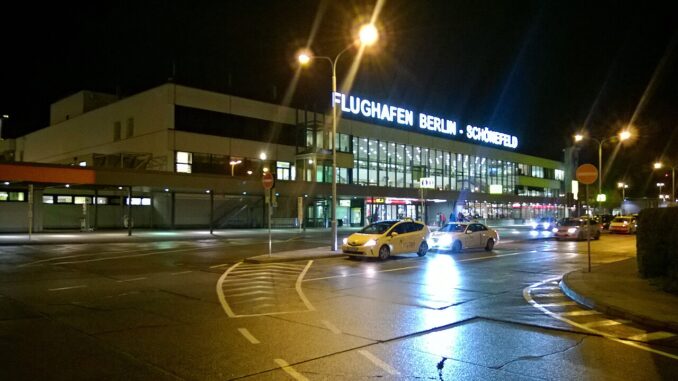 Luchthaven Berlin-Schönefeld bij avond met verlichte terminal en taxi’s voor de ingang