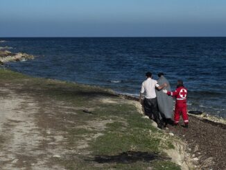 Hulpverlener van het Griekse Rode Kruis begeleidt een Afghaanse vluchteling aan de kust van Lesbos