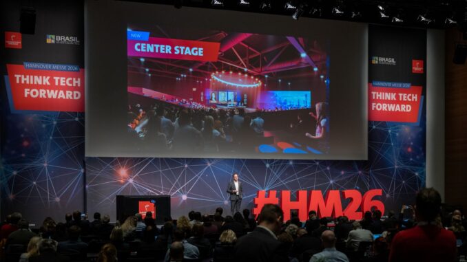 Presentatie over cybersecurity en AI tijdens de Hannover Messe 2026 met #HM26 op het podium