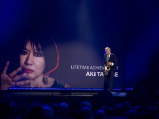 Groot portret van Aki Takase op scherm tijdens Deutscher Jazzpreis 2026 in Bremen, terwijl saxofonist Daniel Erdmann optreedt