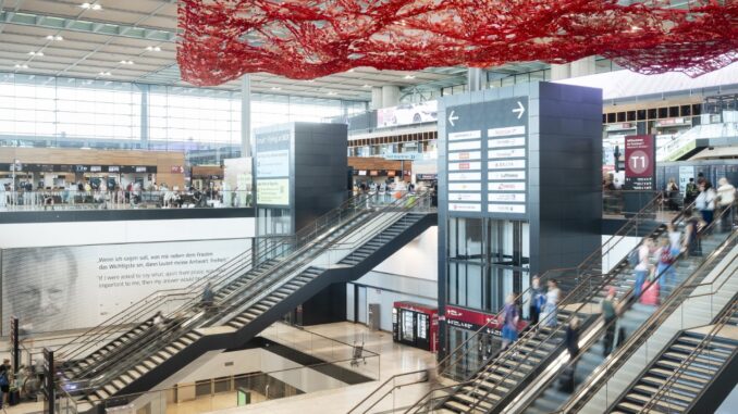 Binnenruimte van Terminal 1 op luchthaven BER in Berlijn met roltrappen en reizigers