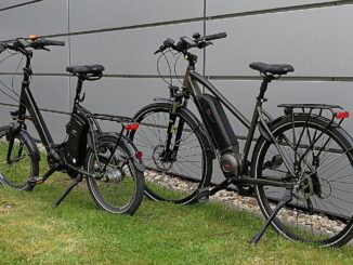 Twee e-bikes, een compacte en een trekkingfiets, geparkeerd naast een muur