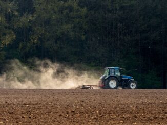 Tractor werkt op een landbouwveld in Duitsland terwijl stofwolken opstijgen