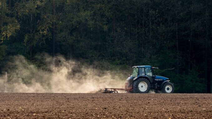 Tractor werkt op een landbouwveld in Duitsland terwijl stofwolken opstijgen