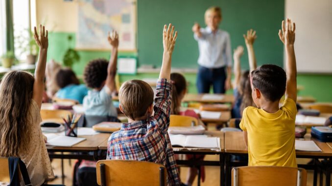Leerlingen steken hun hand op tijdens een les in een klaslokaal