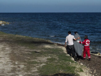Een medewerker van het Griekse Rode Kruis begeleidt een vluchteling na aankomst op het eiland Lesbos.