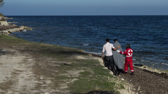 Een medewerker van het Griekse Rode Kruis begeleidt een vluchteling na aankomst op het eiland Lesbos.