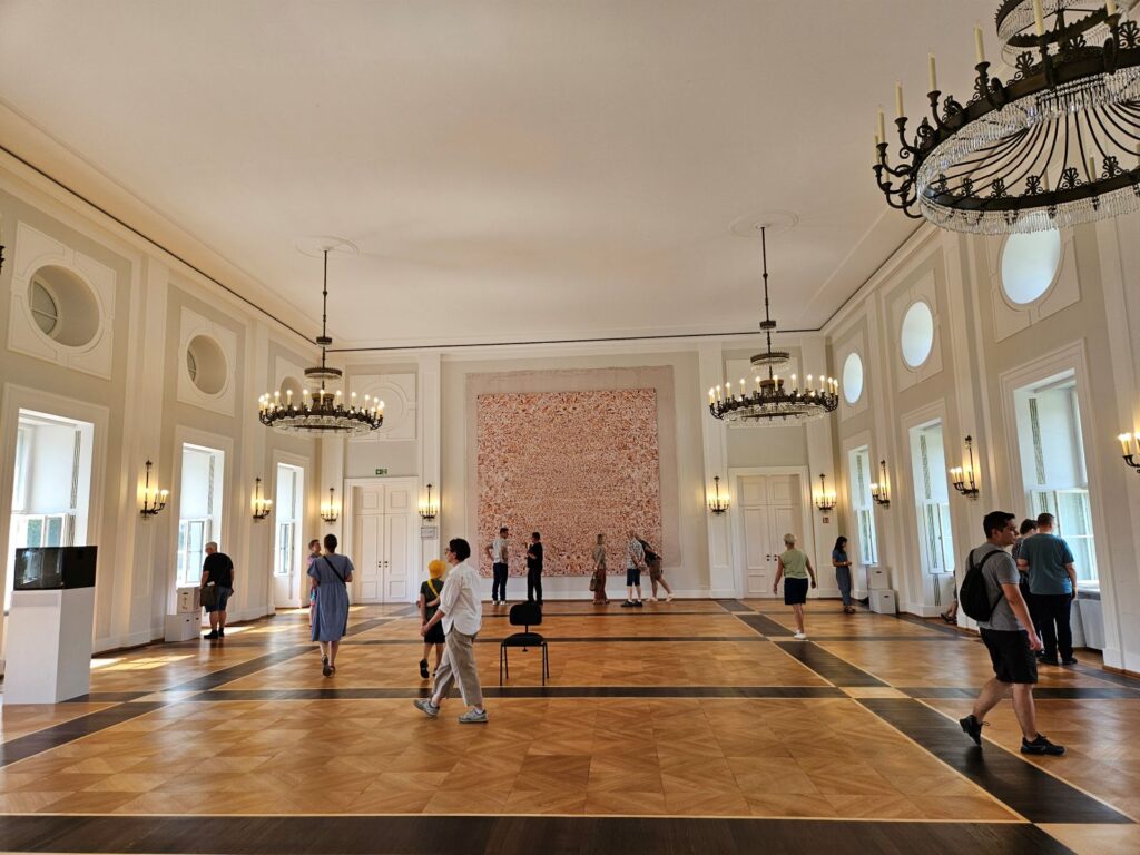 Bezoekers bekijken kunstwerken in de grootste zaal van Schloss Bellevue tijdens de tentoonstelling Freiraum Kunst in Berlijn.
