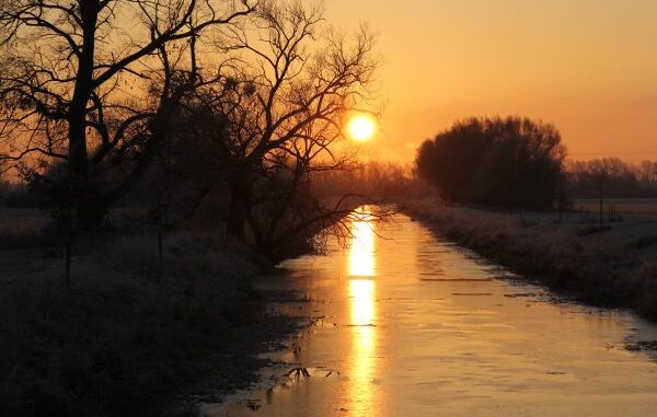 Zonsondergang boven een waterloop tijdens warm zomerweer in Baden-Württemberg