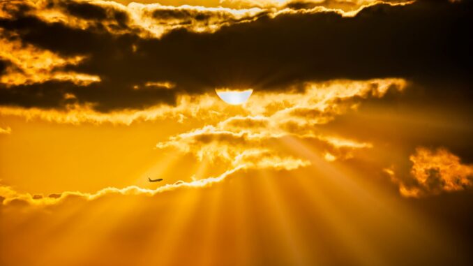 Zonlicht breekt door donkere wolken tijdens warm weer.