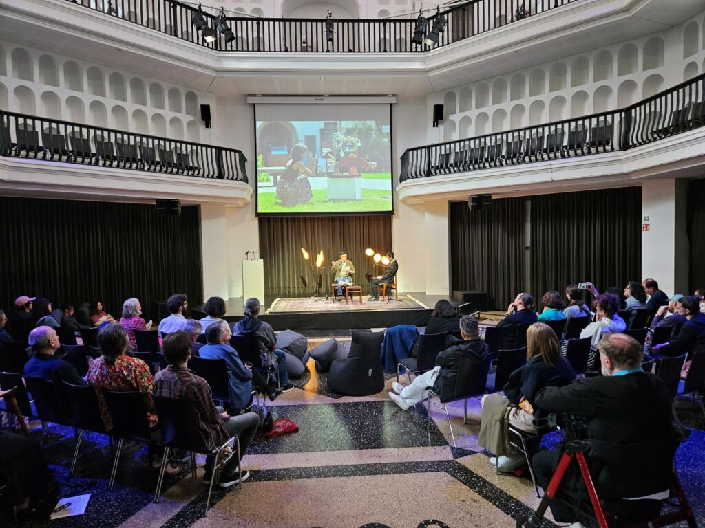 Publiek in de Kuppelhalle van silent green tijdens het Poesiefestival Berlijn 2026 met dichter Yu-Sheng Tsou op het podium