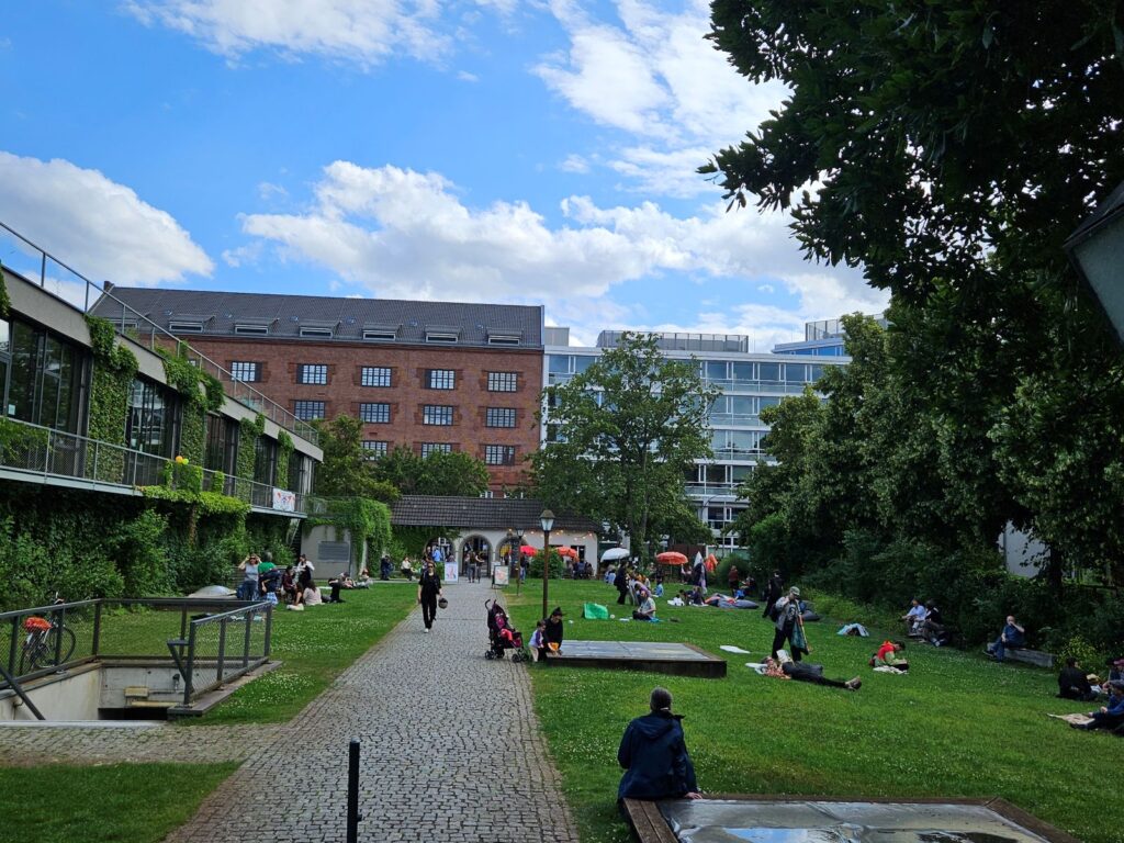 Bezoekers op het groene festivalterrein van silent green tijdens het Poesiefestival Berlijn 2026 in Berlijn