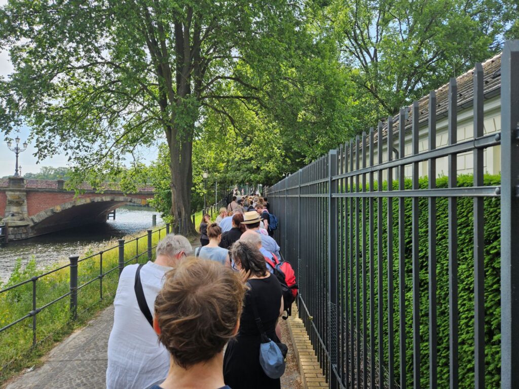 Bezoekers wachten langs het hek van Schloss Bellevue op toegang tot de tentoonstelling Freiraum Kunst in Berlijn.