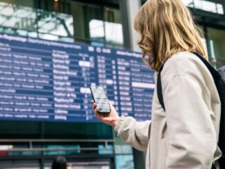 Reiziger bekijkt een smartphone voor het digitale vertrekbord in Berlin Hauptbahnhof.