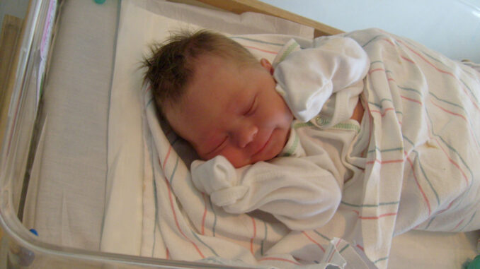 Pasgeboren baby in een ziekenhuisbed als illustratie van het dalende geboortecijfer in Duitsland.