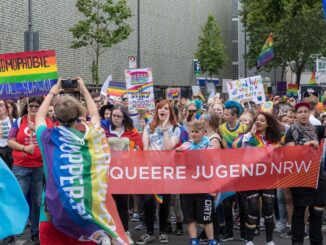 Deelnemers aan ColognePride met een spandoek van Queere Jugend NRW
