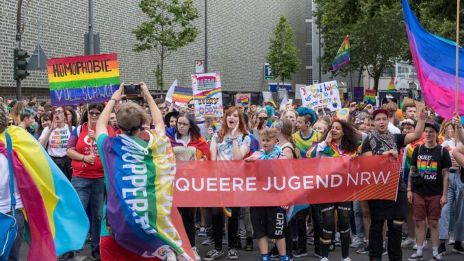 Deelnemers aan ColognePride met een spandoek van Queere Jugend NRW